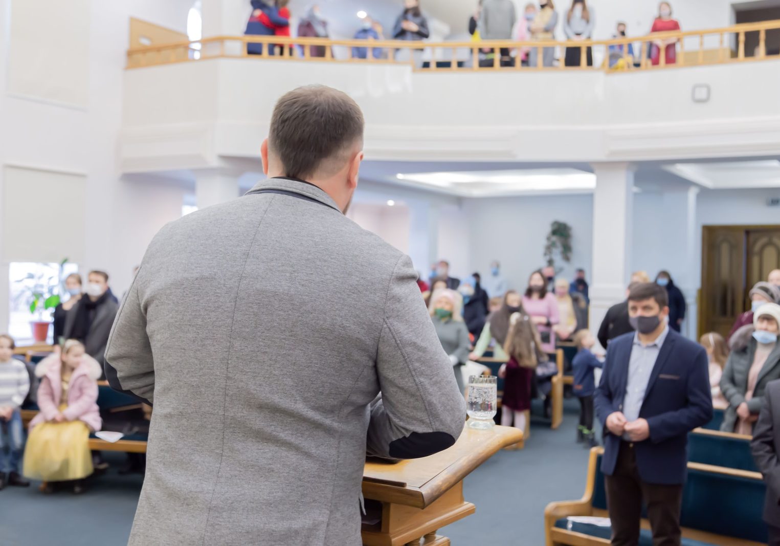 man in gray long sleeve shirt standing in front of brown wooden table